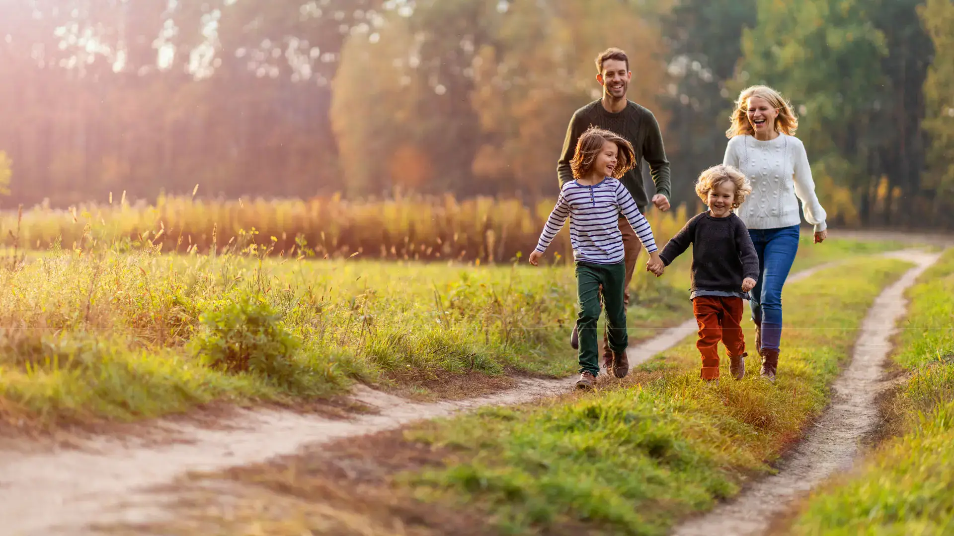 A family of four hikes a trail in a green landscape.