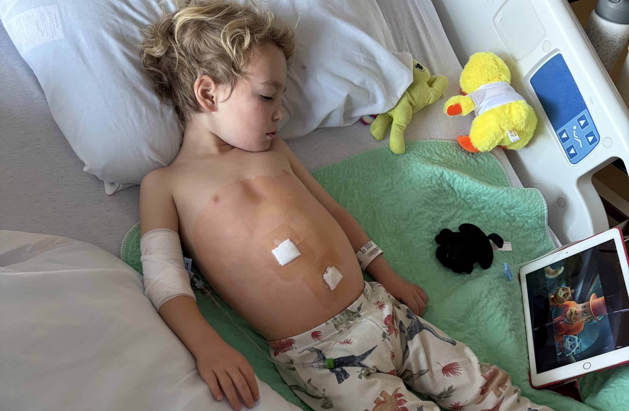 Little boy in the hospital, watching a movie on an ipad.